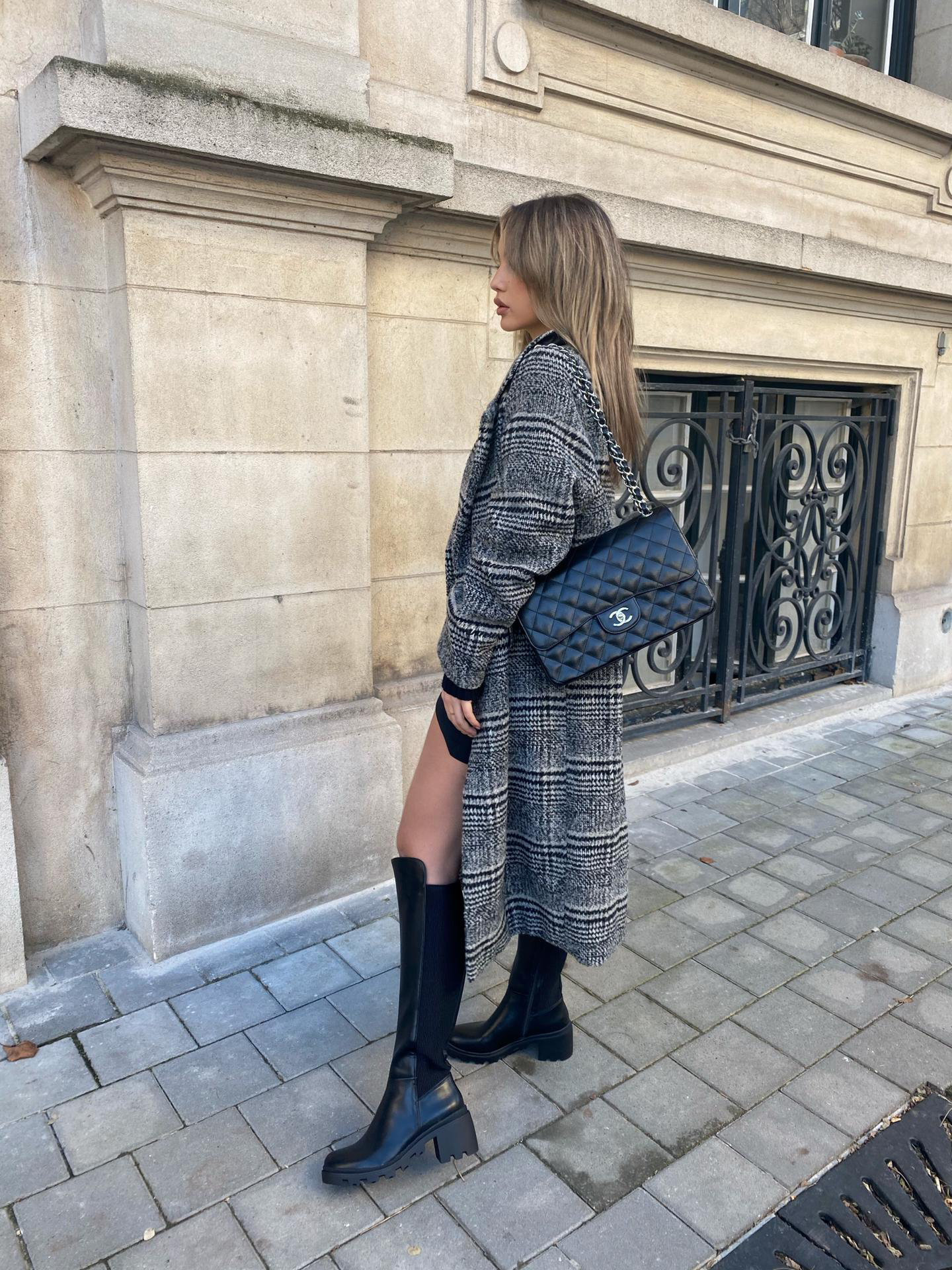 Fille avec des cuissardes et un manteau long dans les rues de Paris